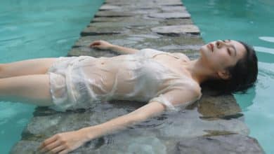 Femme allongee sur marche immergee dans piscine turquoise