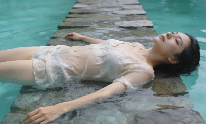 Femme allongee sur marche immergee dans piscine turquoise