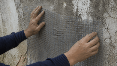 Mains tendant un filet metallique souple contre mur