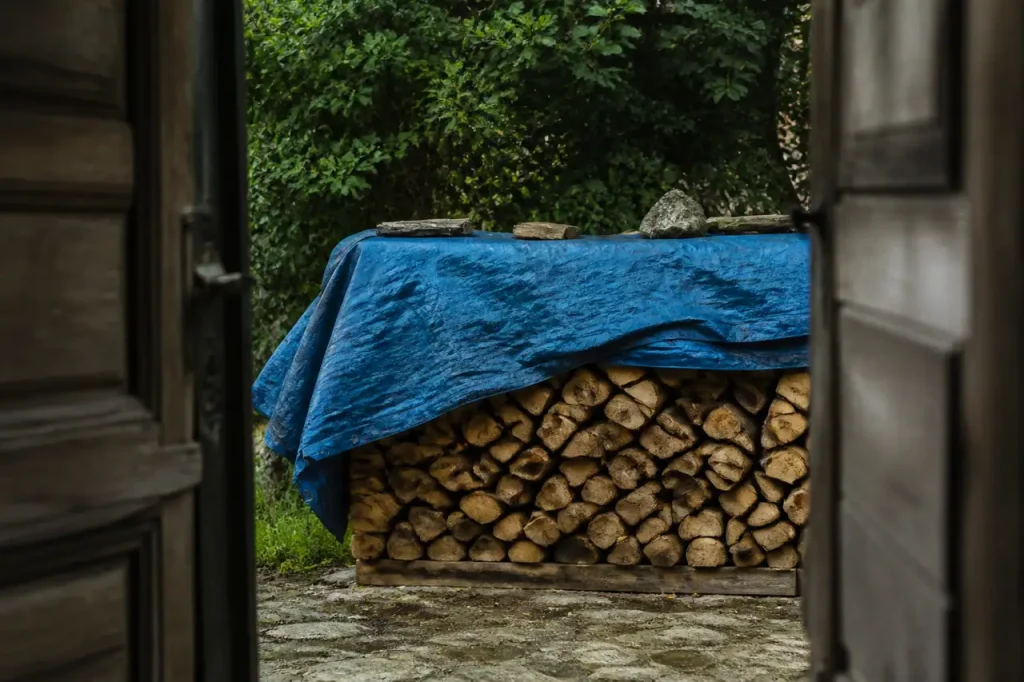 Tas de bois sous une toile bleue tendue